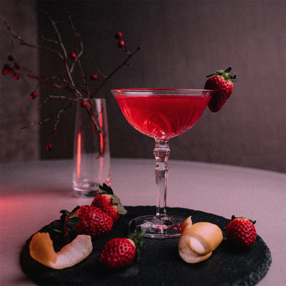 red cocktail with strawberry on the table